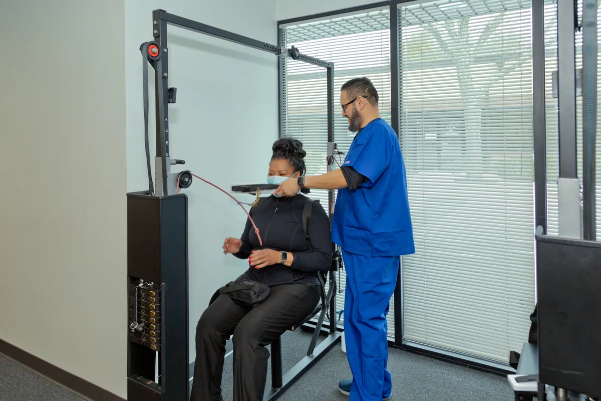 Chiropractic assistant helping a patient on a posture and spinal alignment machine