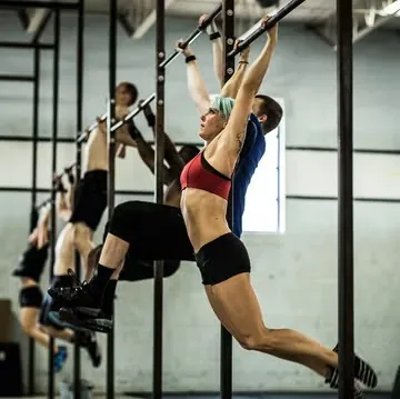 Several athletes doing pull-ups on bars in a gym.