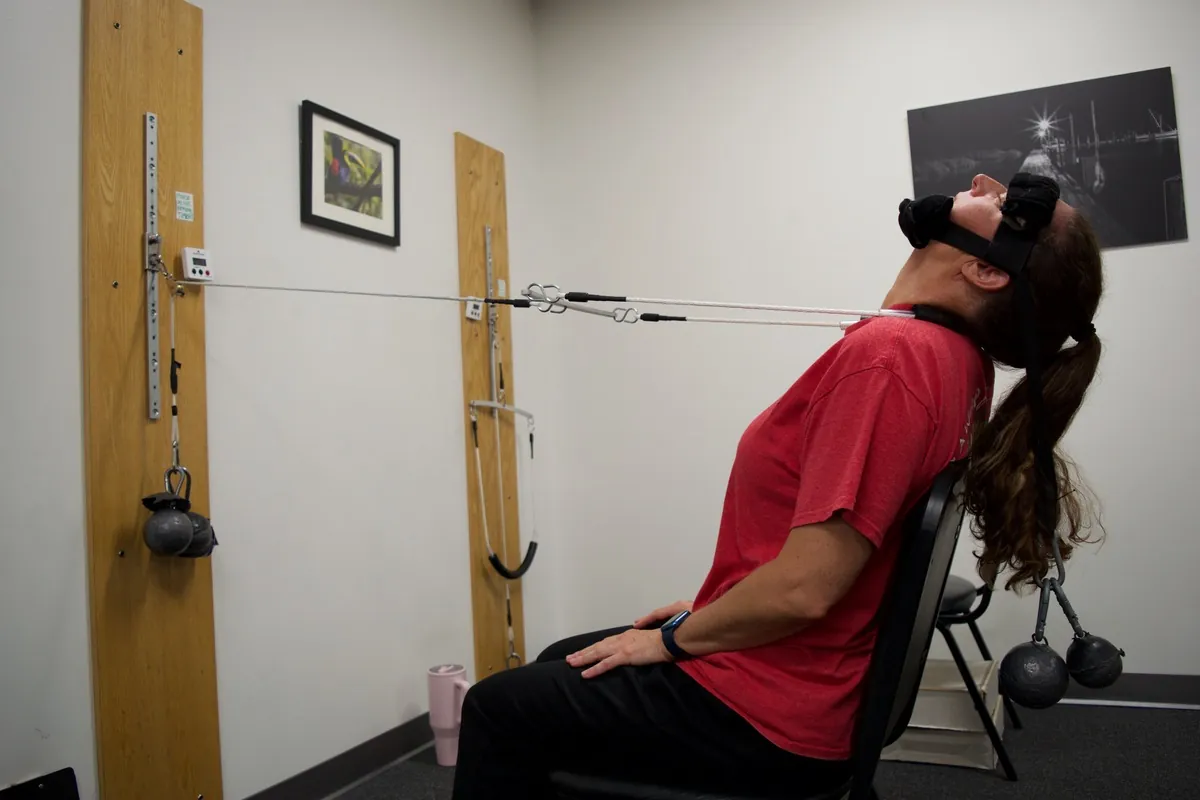 Patient seated in a cervical traction harness for neck pain relief