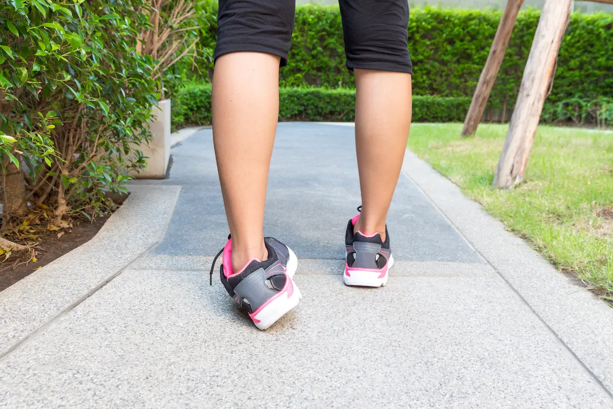 Person's lower legs and sneakers on a path with the ankles rolling outward.